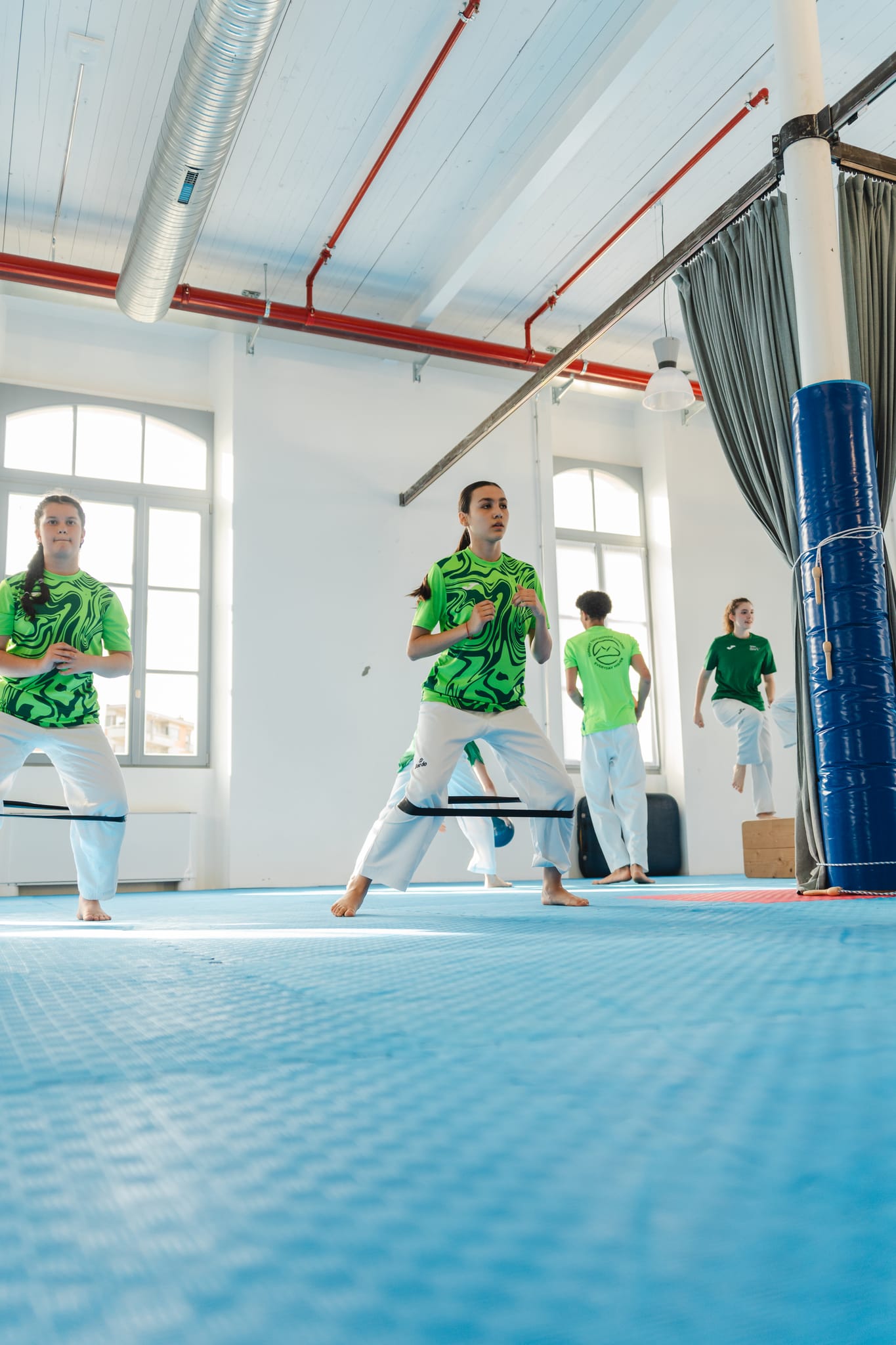 Giovane atleta con elastico di resistenza si allena davanti alla rastrelliera di caschi e protezioni della palestra